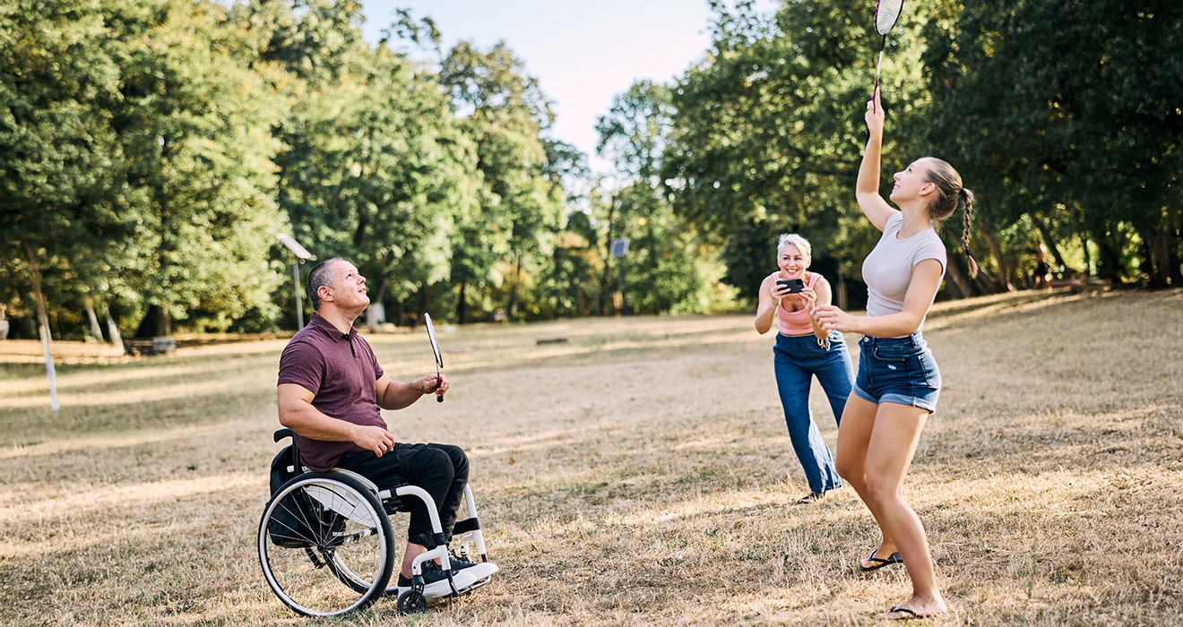 Familie im Ausland, mit Rollstuhl im Park, Federball spielend