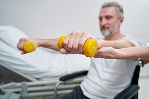 Rollstuhl mieten in der Reha-Phase: So bleiben Sie mobil und unabhängig – Person im Rollstuhl absolviert eine leichte Übung mit physiotherapeutischer Unterstützung