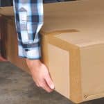 Zusteller liefert ein Rollstuhl-Paket an eine Haustür