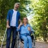 Mann mit Gehhilfe und Frau im Rollstuhl